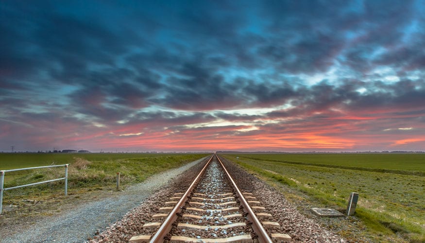 Dissapearing railroad on the horizon under a blue and red sky as a concept for future successfullness.