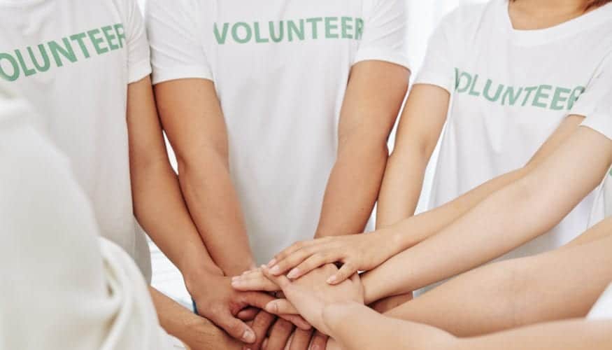 Group of volunteers stacking hands to support each other and express common girl