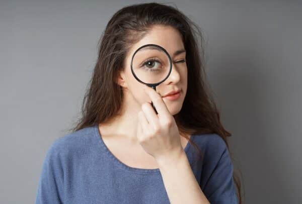 young woman looking through magnifying glass - detective spy audit search concept