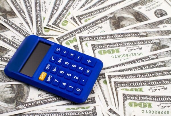 Blue calculator on a pile of dollars. Calculating money concept.