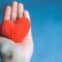 Close up shot of hand holding soft red heart on blue background. Happy Valentine, love, care, volunteering and donation concept. Selective focus